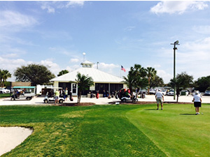 Course greens wit club in background and golfers playing 